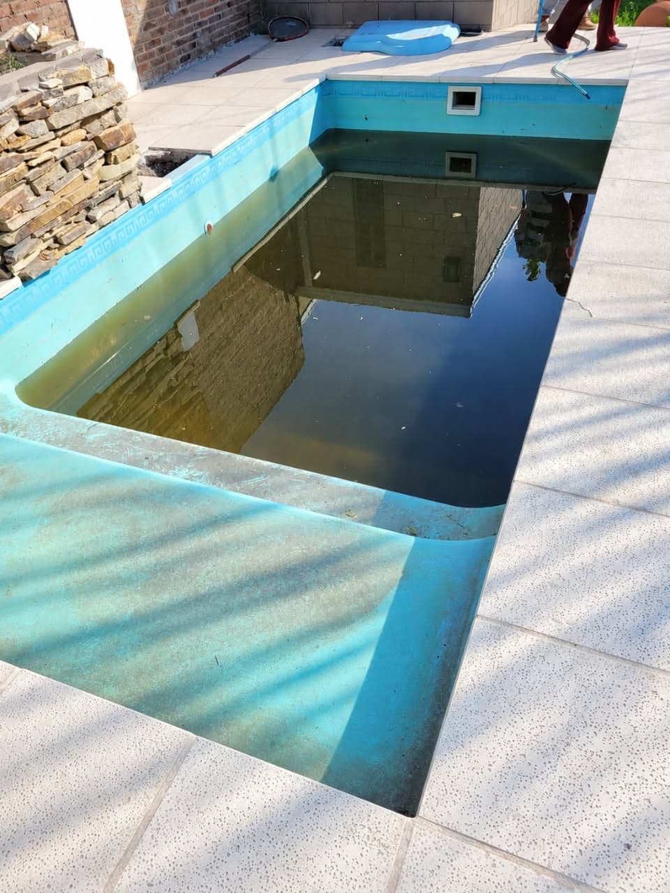 Piscina de fibra gastada, con manchas y agua estancada